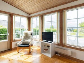 A room with large windows, a television on a stand, a chair, and a radiator.