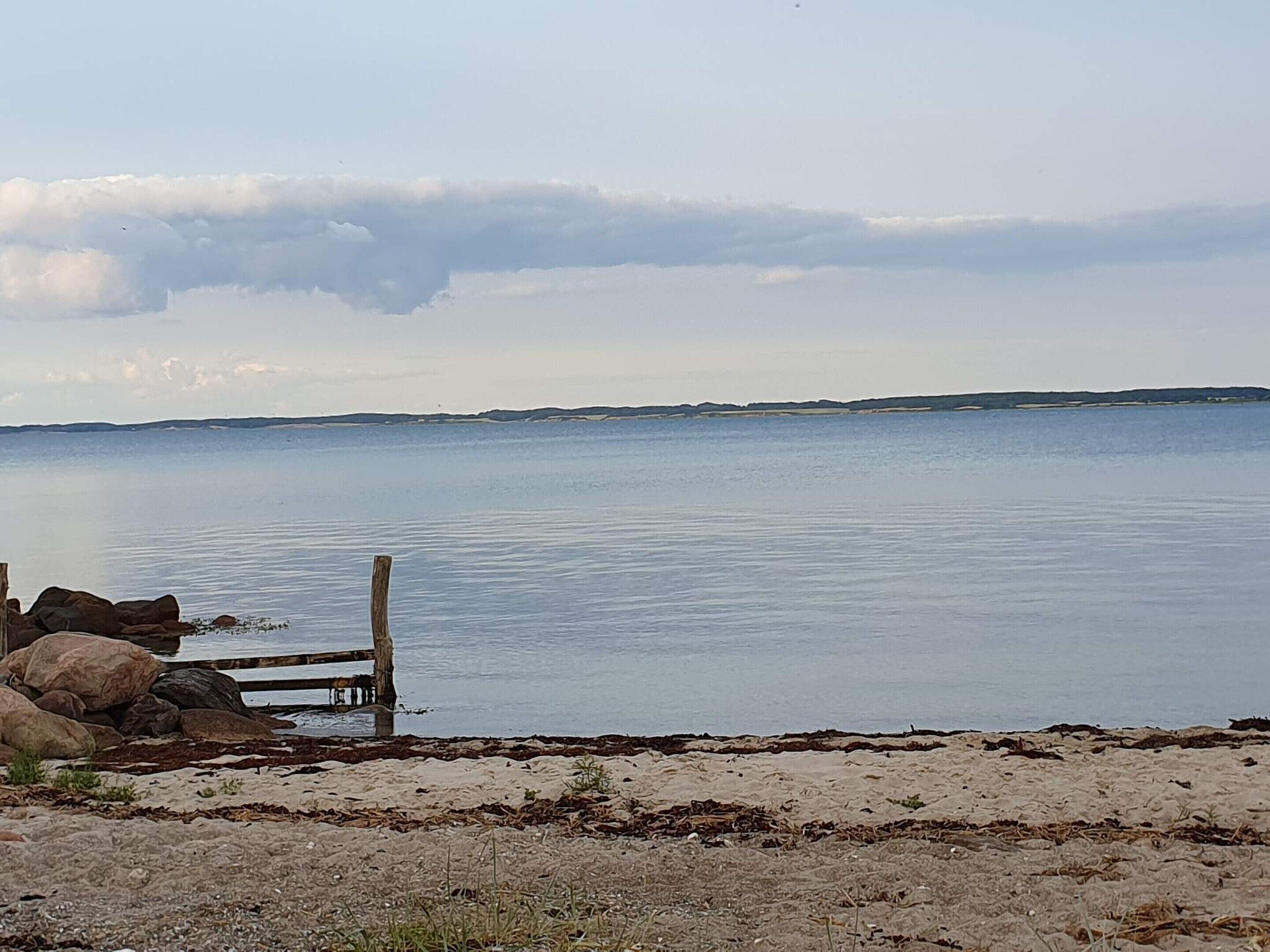 A calm body of water with a wooden fence and rocks in the foreground.