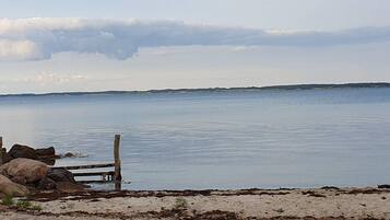A calm body of water with a wooden fence and rocks in the foreground.