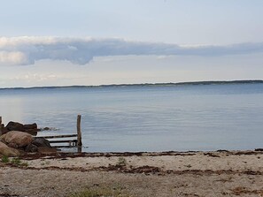 A calm body of water with a wooden fence and rocks in the foreground. - 7 Person Holiday Home in Svendborg (Svendborg)