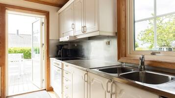 A kitchen with white cabinets, a stainless steel sink, and a window overlooking a green outdoor area.