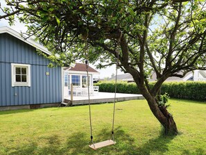 Una casa con un porche, una hamaca y un árbol.