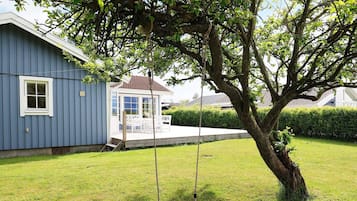 Ein Haus mit einer Veranda, einer Schaukel und einem Baum.