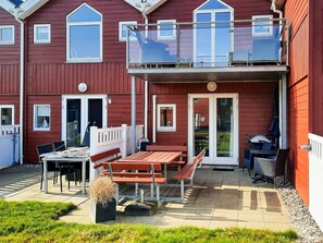 A red building with a balcony, outdoor seating, and a table.
