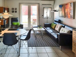 A modern living room with a sofa, chairs, a coffee table, and a dining area. - 6 Person Holiday Home in Hadsund (Hadsund)