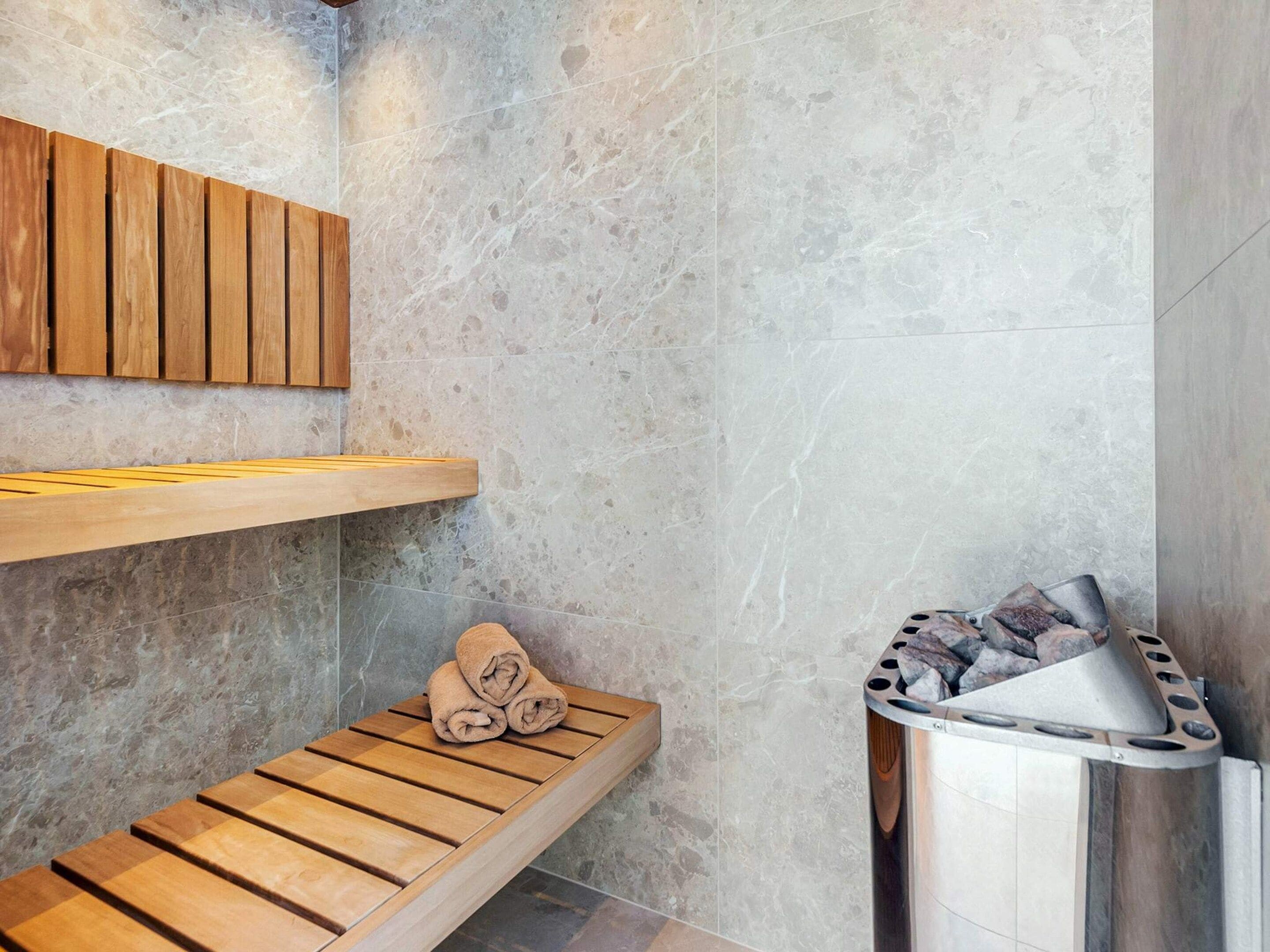 A modern bathroom with a wooden bench, a towel, and a sauna.