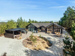 Eine moderne Hütte mit überdachter Außenlounge, einem Whirlpool und einer großen Terrasse.