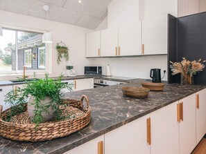 A modern kitchen with white cabinets, a marble countertop, and a large window.