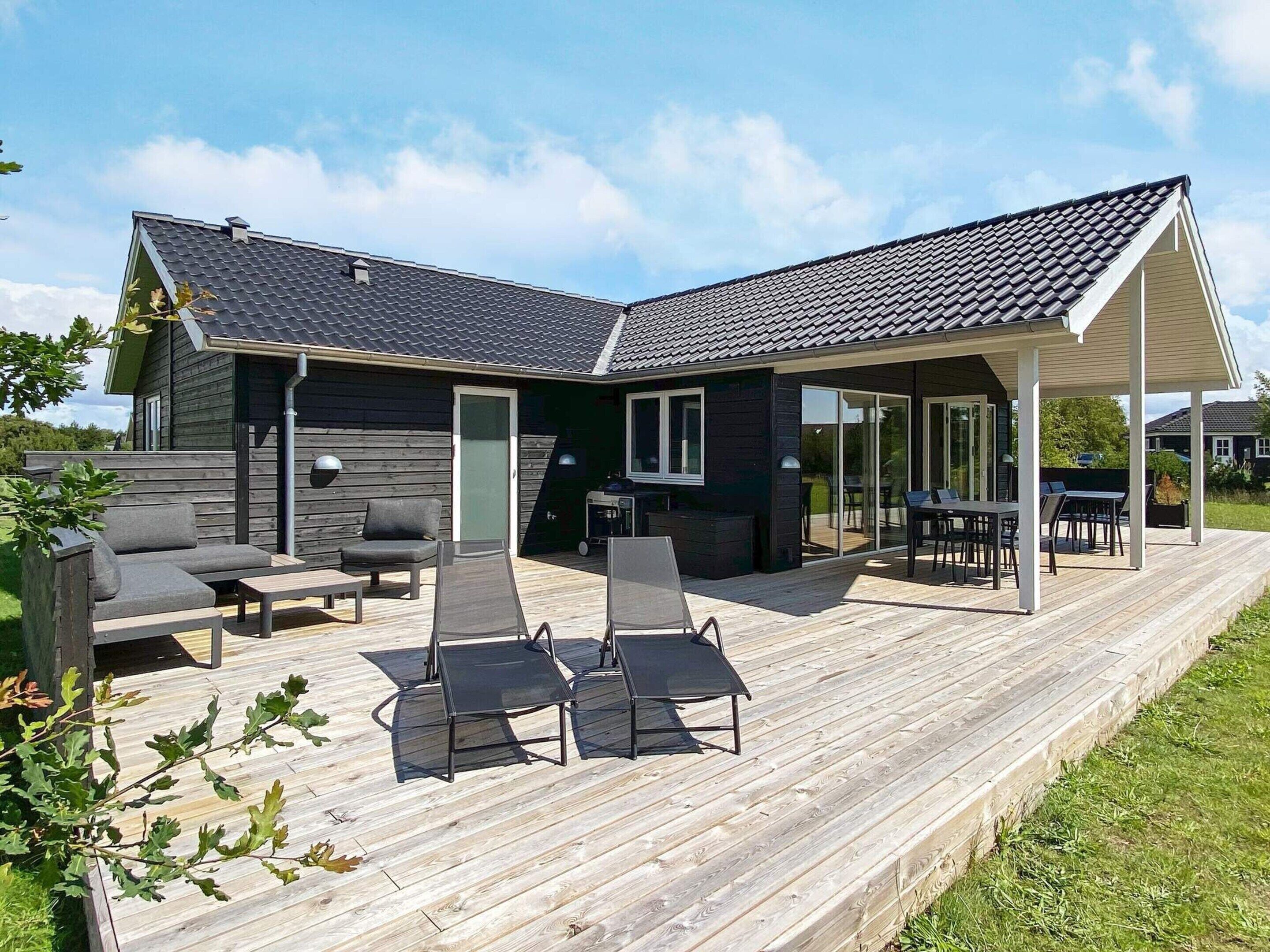 Ett modernt hus med en täckt uteplats, utemöbler och en terrass.