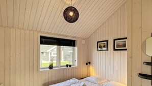 A bedroom with two beds, a window with a view of a house, and a hanging light fixture. - 8 Person Holiday Home in Vaeggerlose (Vaeggerlose)
