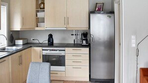 A modern kitchen with light wood cabinets, a stainless steel refrigerator, a built-in oven, and a coffee maker. - 6 Person Holiday Home in Gursken-by Traum (Sande)