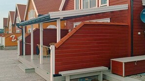 A row of wooden houses with red roofs and white trim, each with a porch and a bench. - 6 Person Holiday Home in Gursken-by Traum (Sande)