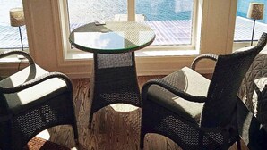 A room with a large window overlooking the sea, a round glass table, and two wicker chairs. - 6 Person Holiday Home in Gursken-by Traum (Sande)