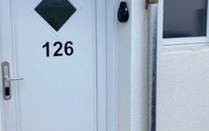 A white door with the number 126 and a small diamond-shaped window.