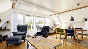 En rummelig loftrum med højt til loftet, et spiseområde og en hyggelig opholdsstue med pejs.