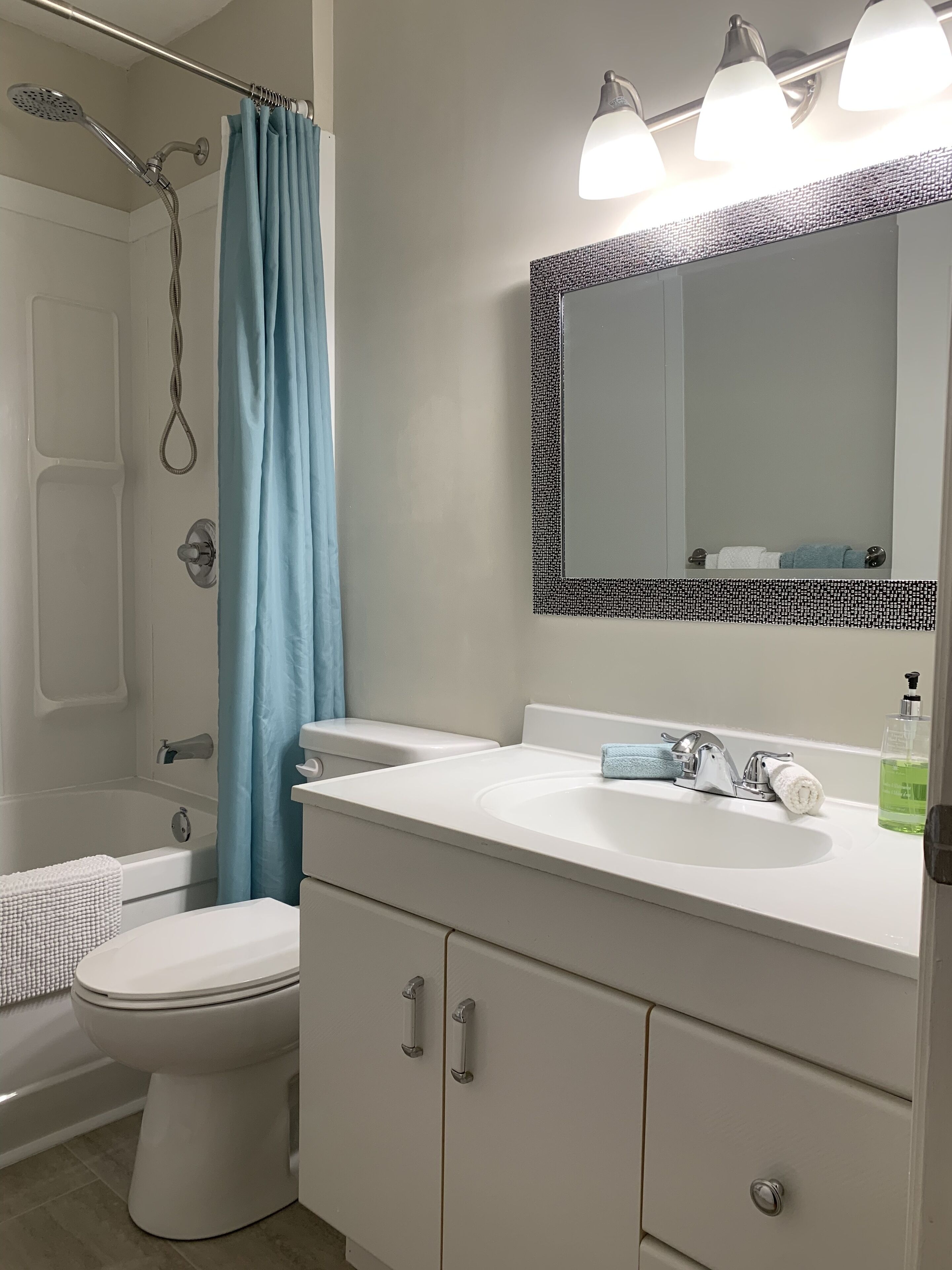 Une salle de bain équipée d’une douche, de toilettes, d’un lavabo et d’un miroir.