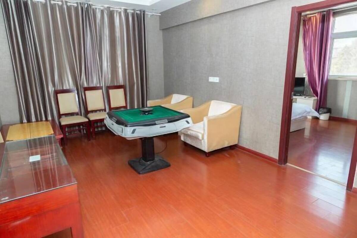 A room with a pool table, two armchairs, a sofa, and a dining table.