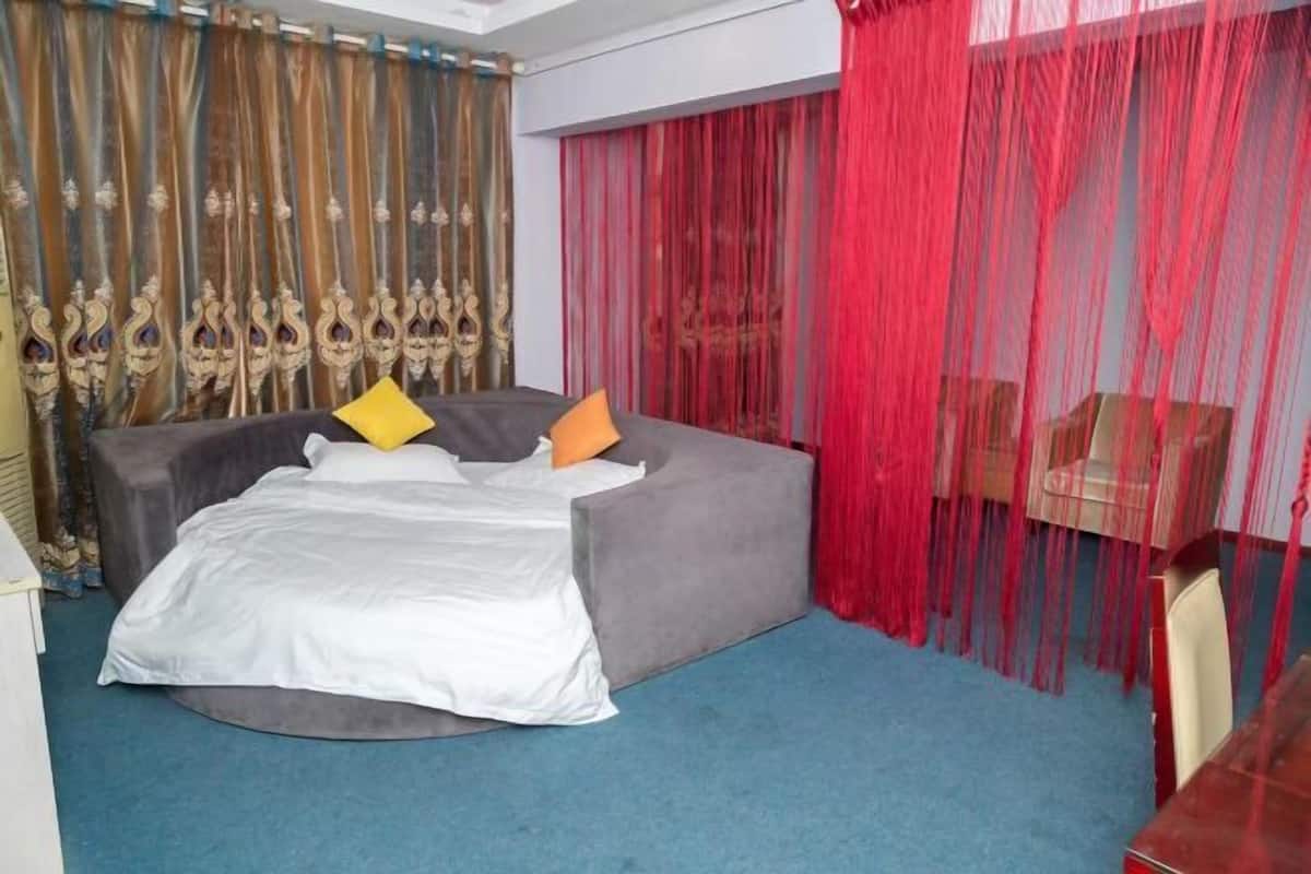 A bed with a white sheet, two pillows, and a grey sofa.