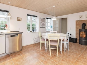 Una cucina con lavastoviglie, un tavolo da pranzo con sedie, un fornello e una finestra vista verde.