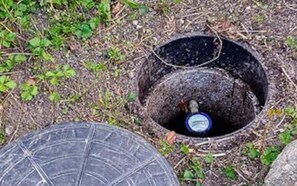 Un trou circulaire dans le sol, avec une bouteille à l’intérieur.
