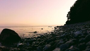 A rocky shoreline with a calm sea and a distant horizon. - 4 Star Holiday Home in Borre (Borre)