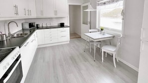 A modern kitchen with white cabinetry, a dining table, and a window with a view. - 8 Person Holiday Home in Halsanaustan-by Traum (Heim)