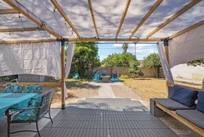 Relax under a shaded pergola with a table and chairs, surrounded by a serene garden view.