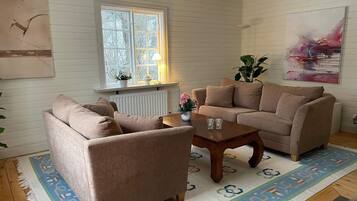 Una sala de estar con un sofá color beige, una mesa de centro de madera y un tapete estampado.