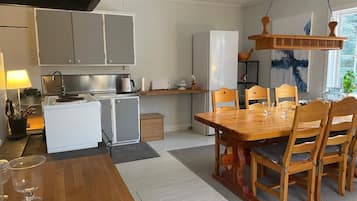 Een kleine keuken met een eethoek, met een houten tafel en stoelen, een koelkast en een kastje.