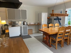 Une cuisine compacte avec un coin repas, comprenant une table et des chaises en bois, un réfrigérateur et un petit meuble de rangement.