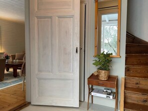 A room with a white door, a wooden staircase, a small table with a plant, and a mirror on the wall. - 6 Person Holiday Home in Jarna (Järna)