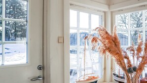 A room with large windows, a wooden table, and a model sailboat. - 8 Person Holiday Home in Songe (Tvedestrand)