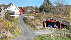 A rural road leading to a small village with houses, a red building, and a stone wall. - 8 Person Holiday Home in Songe (Tvedestrand)