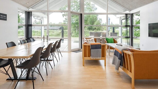 A spacious room with a large table and chairs, a sofa, and a television. - 8 Person Holiday Home in Hals (Hals)