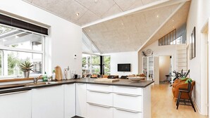 A modern kitchen with a large island, white cabinetry, and a view to the outdoors. - 8 Person Holiday Home in Hals (Hals)