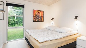 Ein modernes Schlafzimmer mit großem Fenster, einem Bett mit weißer Bettwäsche, zwei Nachttischlampen und einem farbenfrohen, abstrakten Gemälde an der Wand.