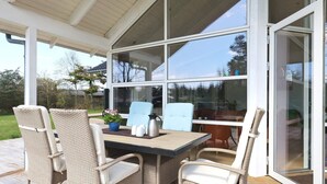 Eine überdachte Terrasse mit Korbmöbeln, einem Tisch und einer Kaffeemaschine.