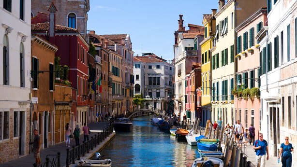 Een smalle gracht in een historische Europese stad met kleurrijke gebouwen aan weerszijden.