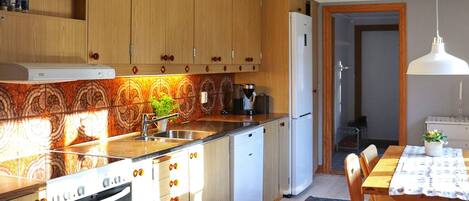 A kitchen with wooden cabinets, a built-in oven, a refrigerator, and a dining area with a table and chairs.