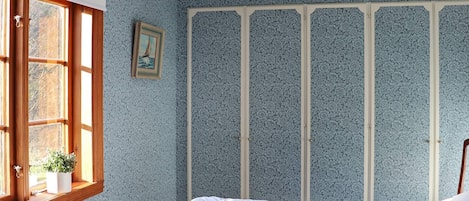 A bedroom with a bed, a window with a view, and a radiator.