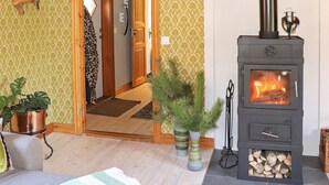 A room with a wooden door, a fireplace with visible logs, and two potted plants. - 4 Star Holiday Home in Ullared (Ullared)