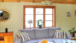 A living room with a sofa, two round tables, a mirror, and a window with curtains. - 4 Star Holiday Home in Ullared (Ullared)
