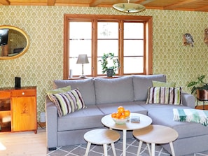 A living room with a sofa, two round tables, a mirror, and a window with curtains. - 4 Star Holiday Home in Ullared (Ullared)