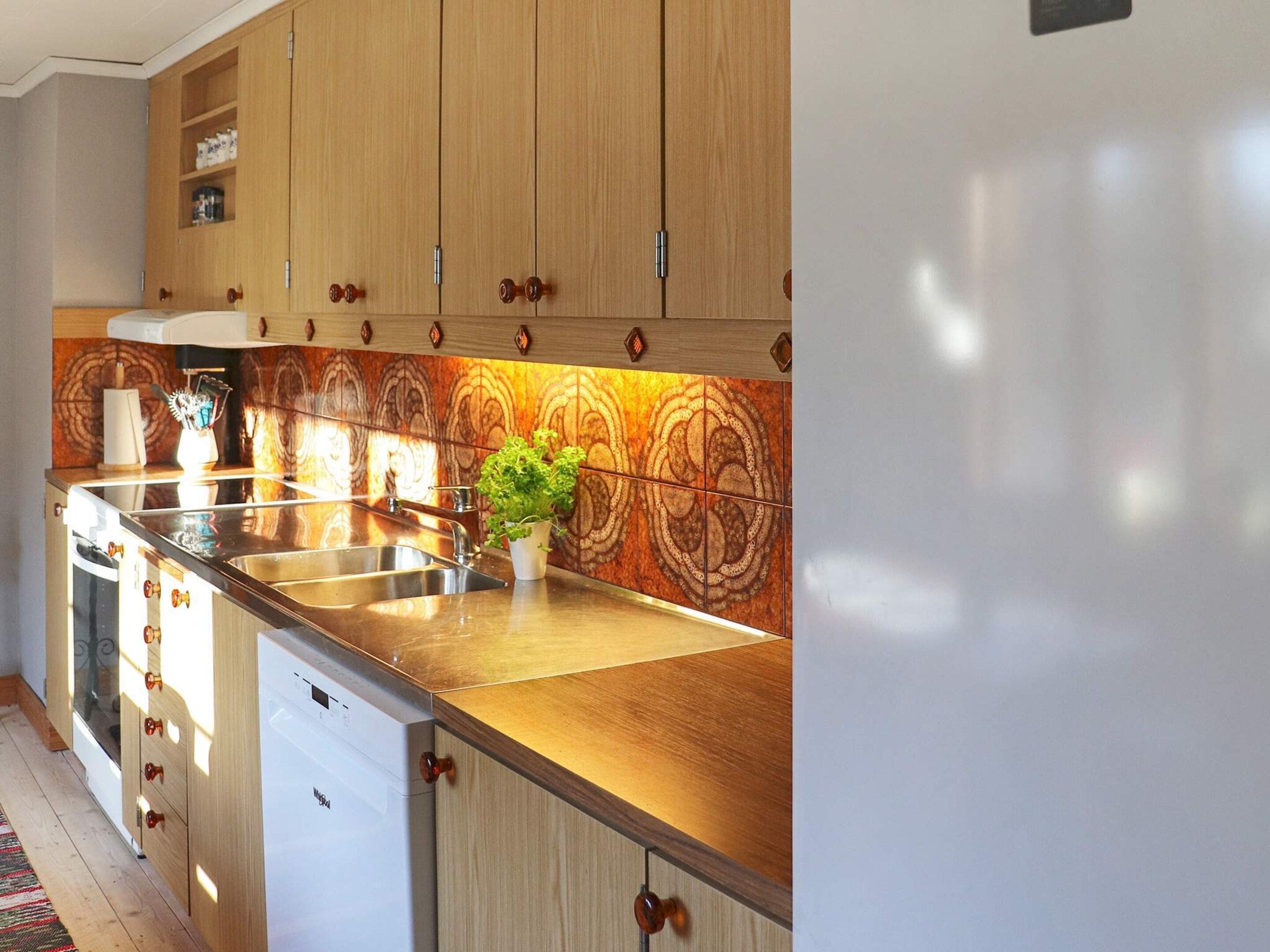 Una cocina con armarios de madera, un fregadero de acero inoxidable y una planta en maceta.