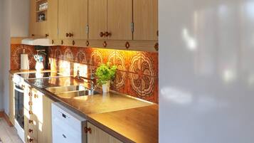 Una cocina con armarios de madera, un fregadero de acero inoxidable y una planta en maceta.
