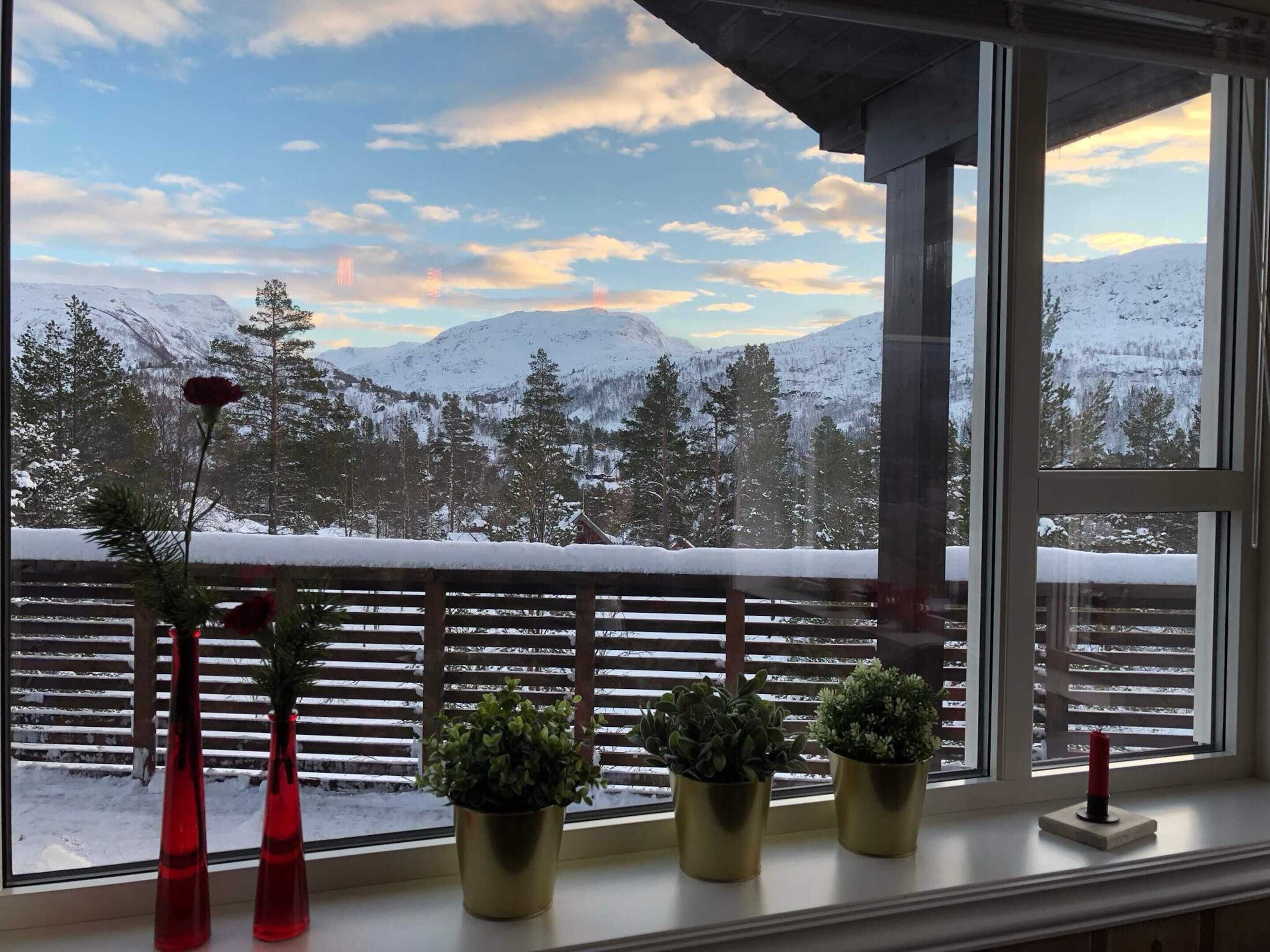 A balcony with a view of snow-covered mountains and a sunset.