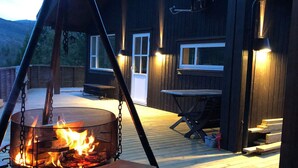 A fire pit on a wooden deck with a view of a building in the background. - 4 Star Holiday Home in Skare (Ullensvang)