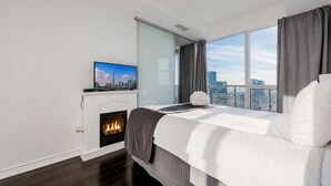 Una habitación de hotel moderna con chimenea, cama, televisión y vista a la ciudad.