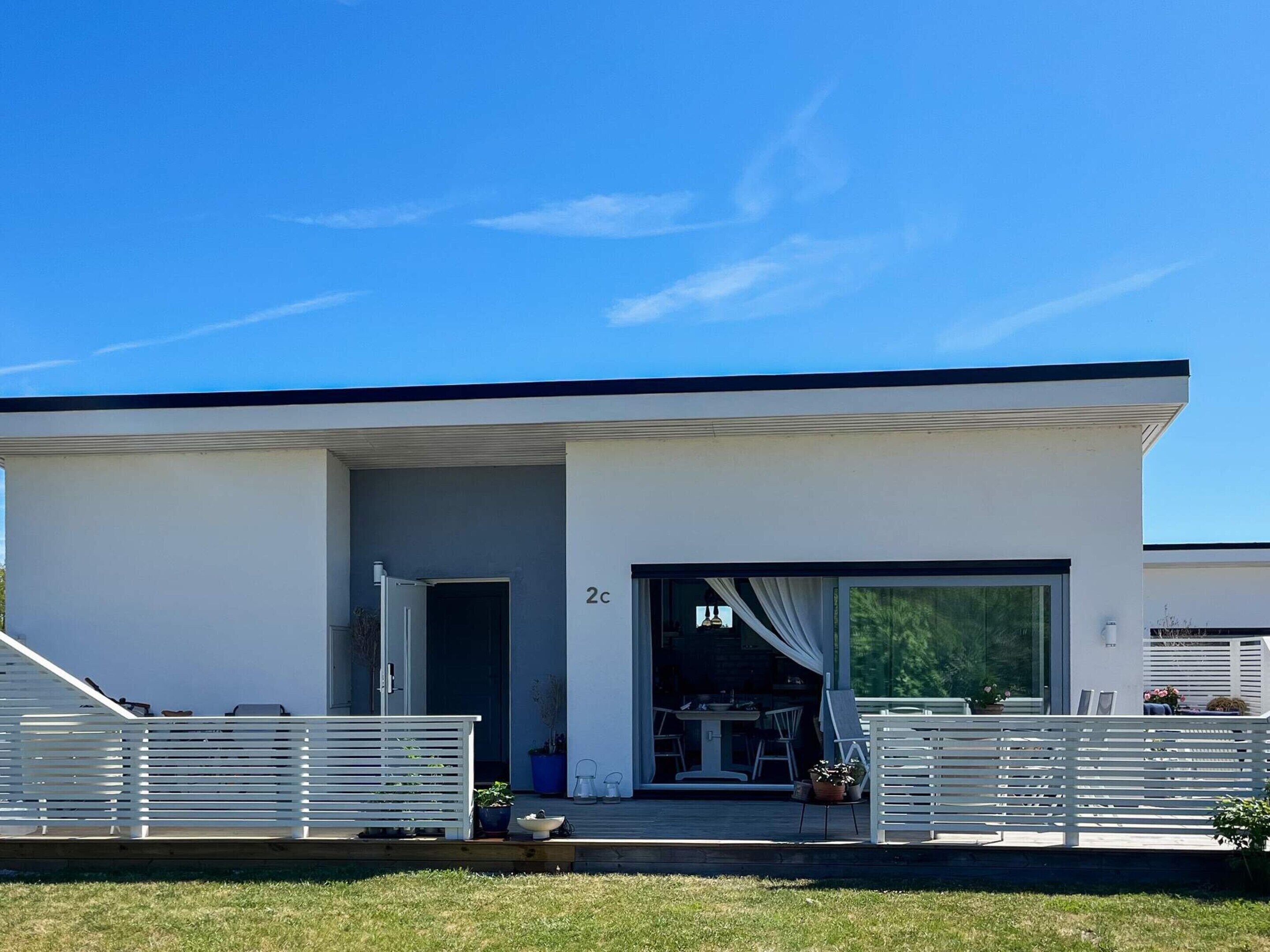 A modern two-story house with a garage, a covered outdoor seating area, and a number '2c' on the facade.