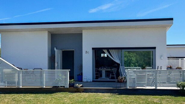 A modern two-story house with a garage, a covered outdoor seating area, and a number '2c' on the facade. - 4 Star Holiday Home in Gotlands Tofta (Gotlands Tofta)